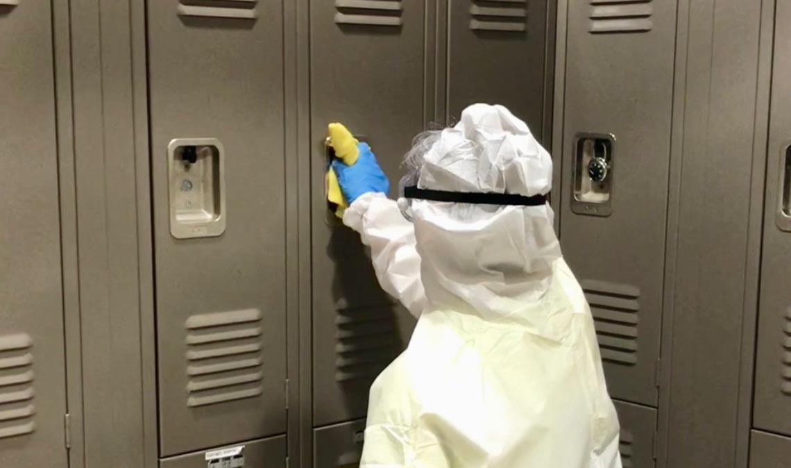 Person in hazmat suit cleaning lockers